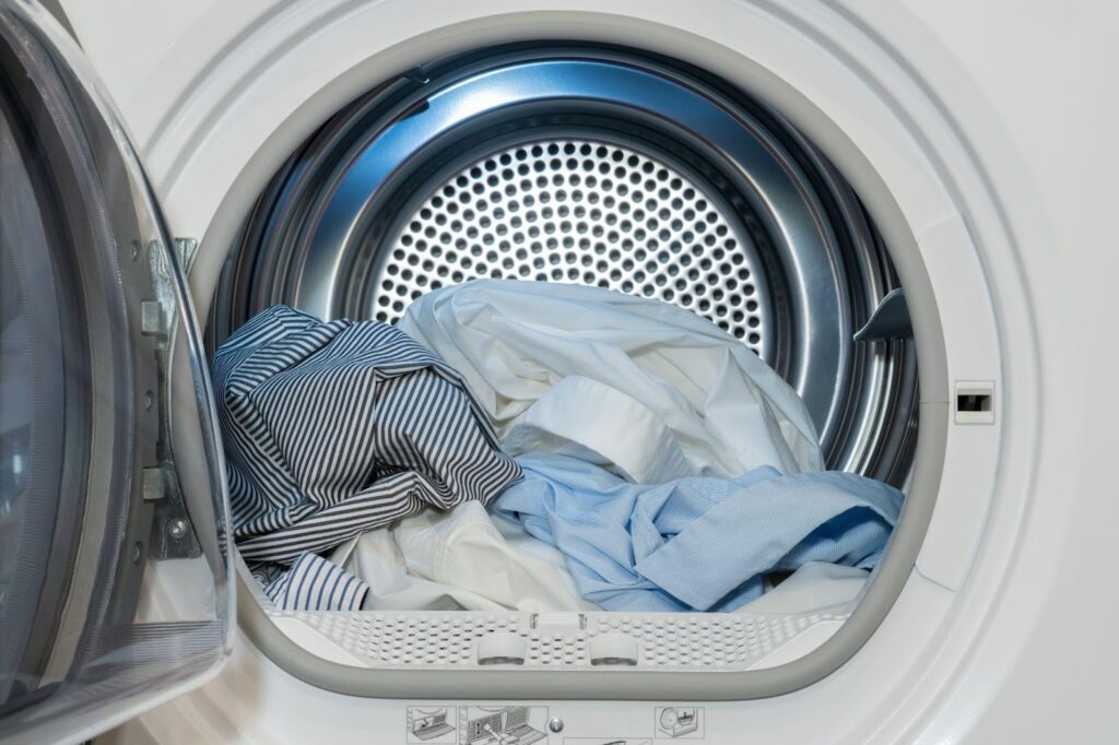 A white washing machine with a load of clothes inside illustrating a typical laundry scene in a home